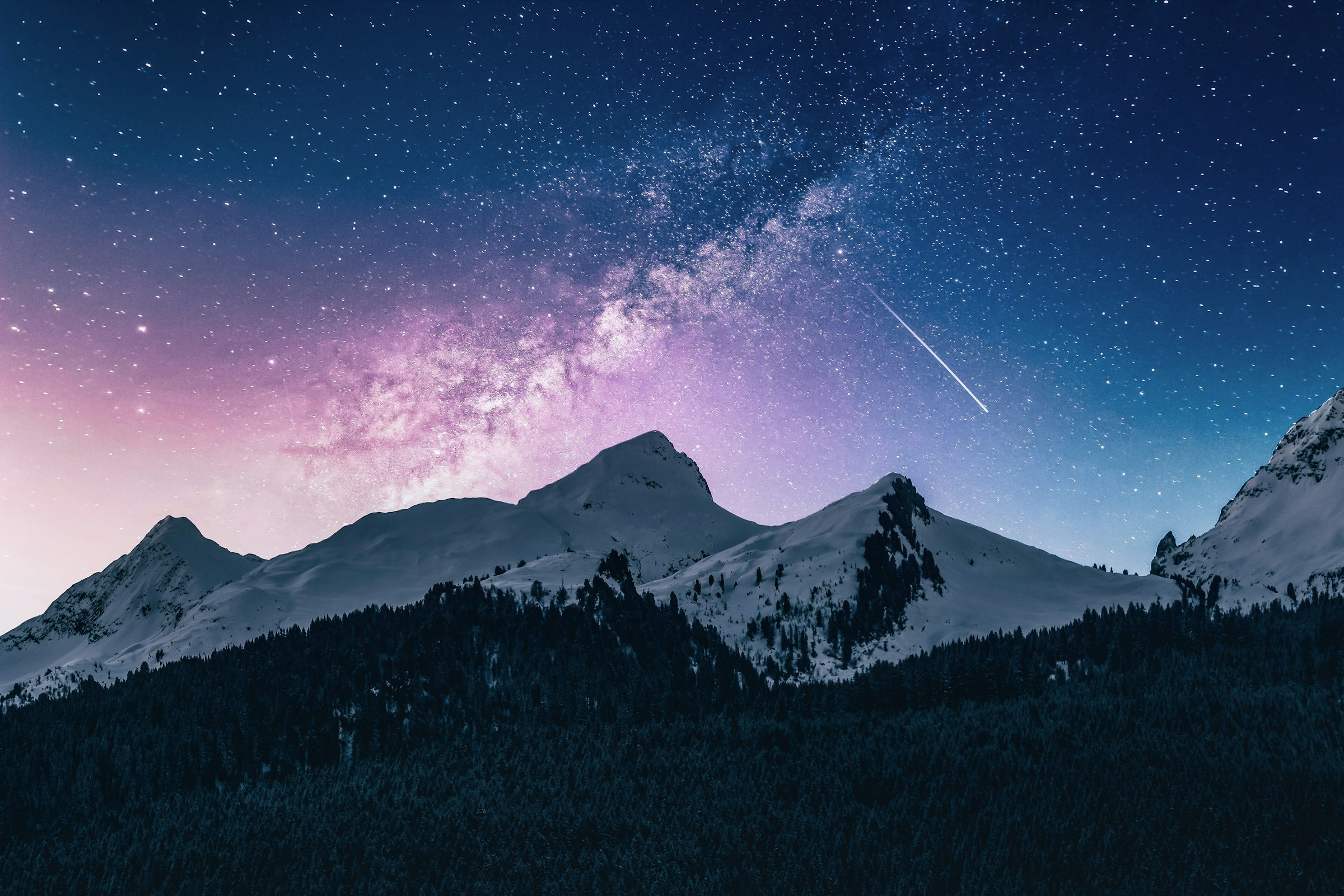 The Milky Way arching above a mountain silhouette at night