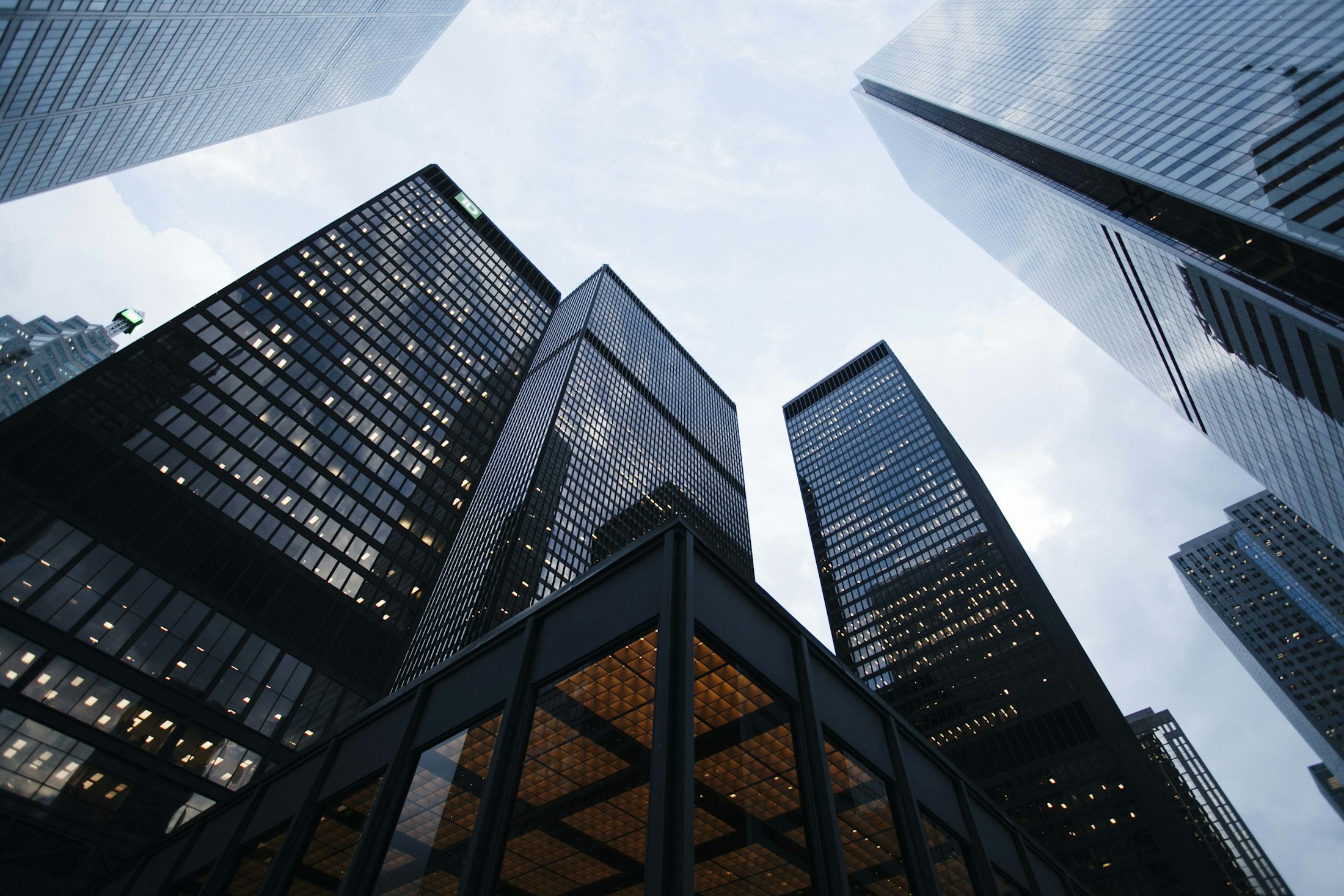 Glass skyscrapers converging towards a cloudy sky, photographed from below