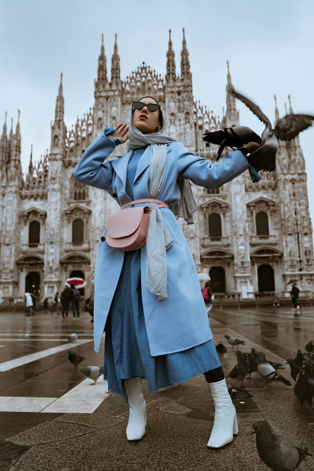 Fashion editorial of a model in a pale blue coat in front of a cathedral