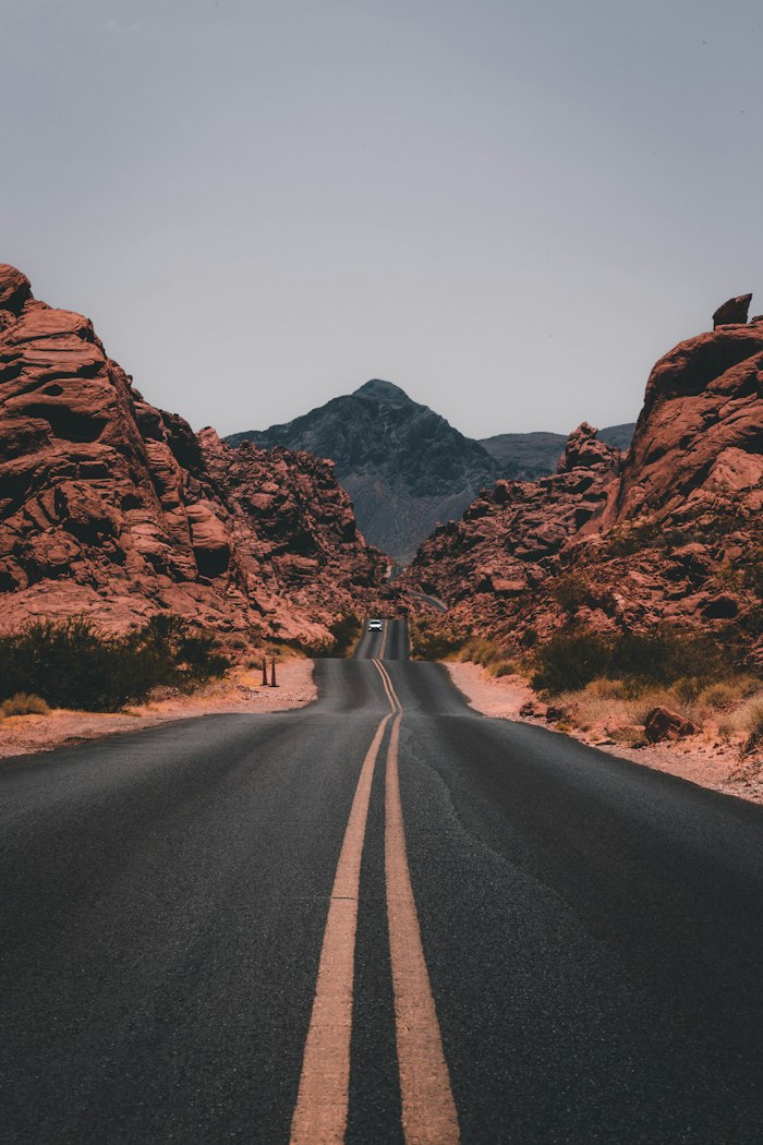 Empty desert road running between red rock canyon walls